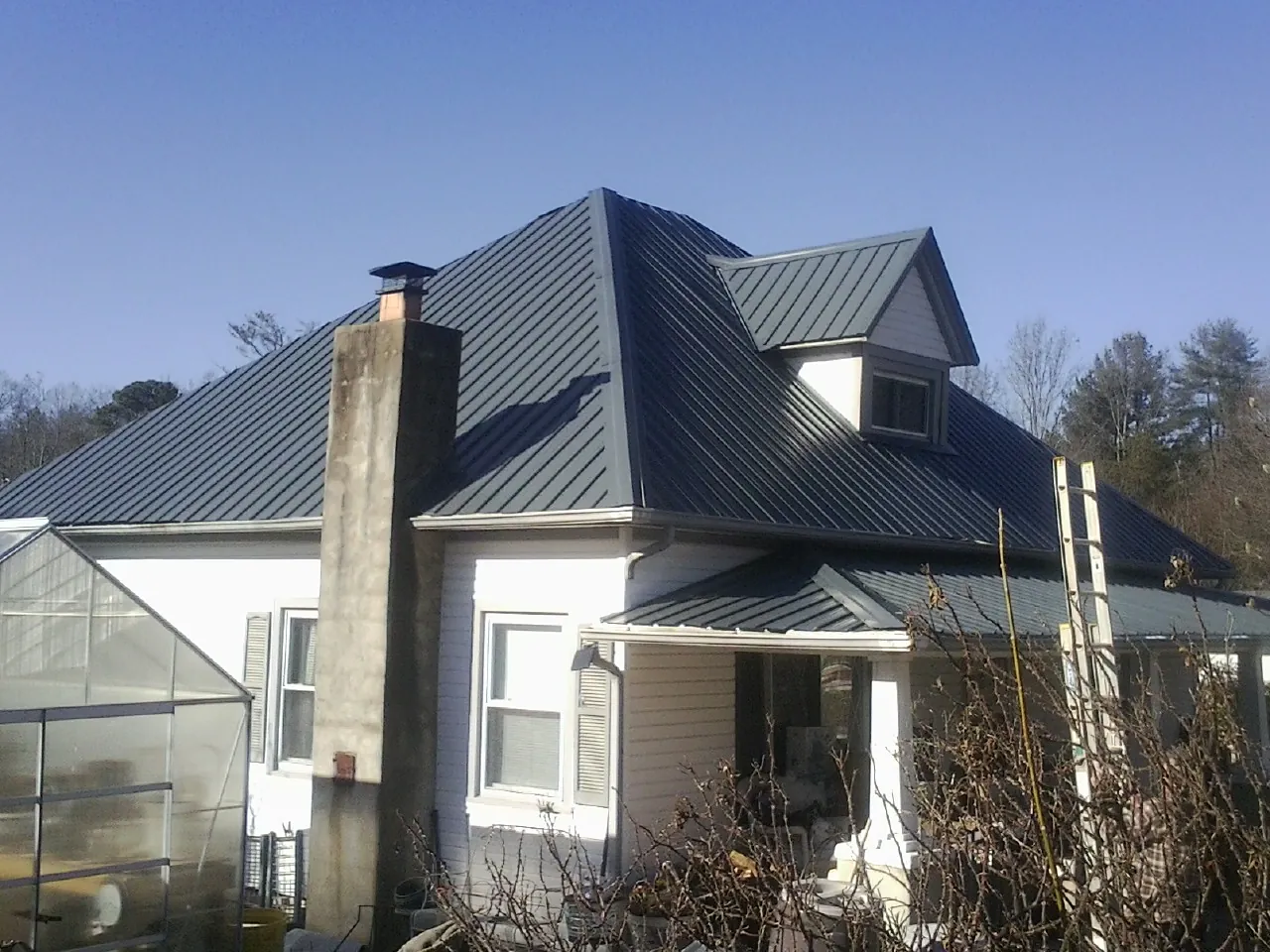 Dark blue standing seam metal roof on a white farmhouse with dormer — Slate & Tile Roof Repair by Roofing Brothers in Coalton