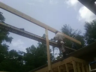 Carpenter setting a ridge beam over a new addition frame — Ice Dam Removal by Roofing Brothers in Coalton