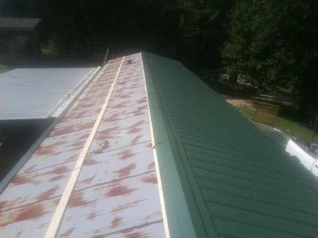 Old rusted panels beside newly installed green metal roofing — Wind Damage Roof Repair by Roofing Brothers in Coalton