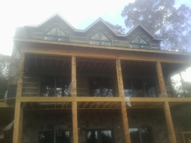 Dormers and porch framing on a large log home under construction — Roof Coating work by our crew in Coalton