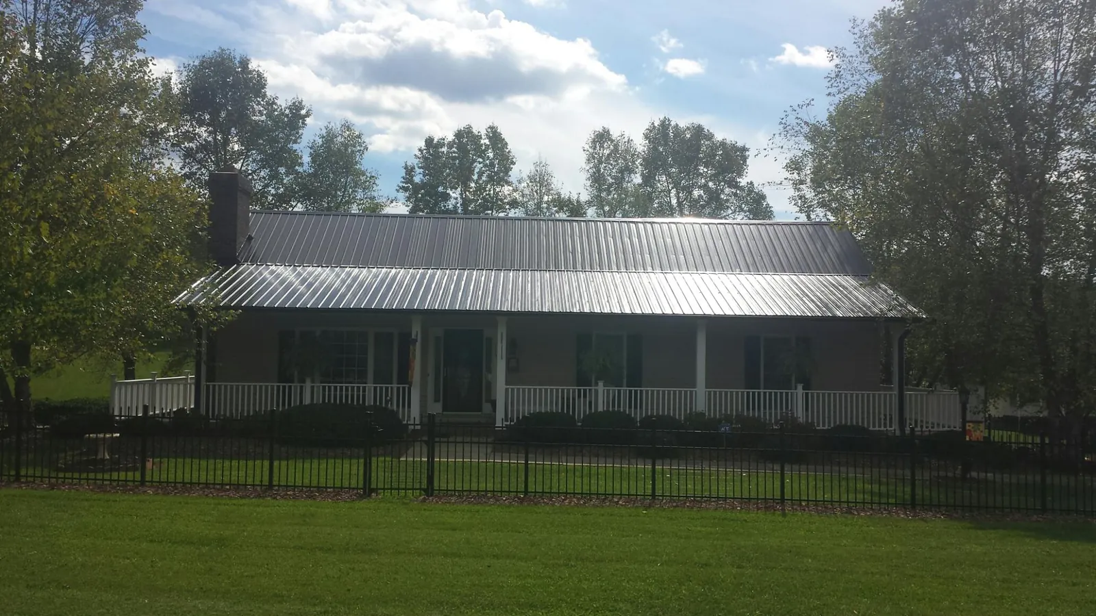 Gray metal roof on a brick ranch with a full width front porch — Gutter Guard Installation work by our crew in Coalton