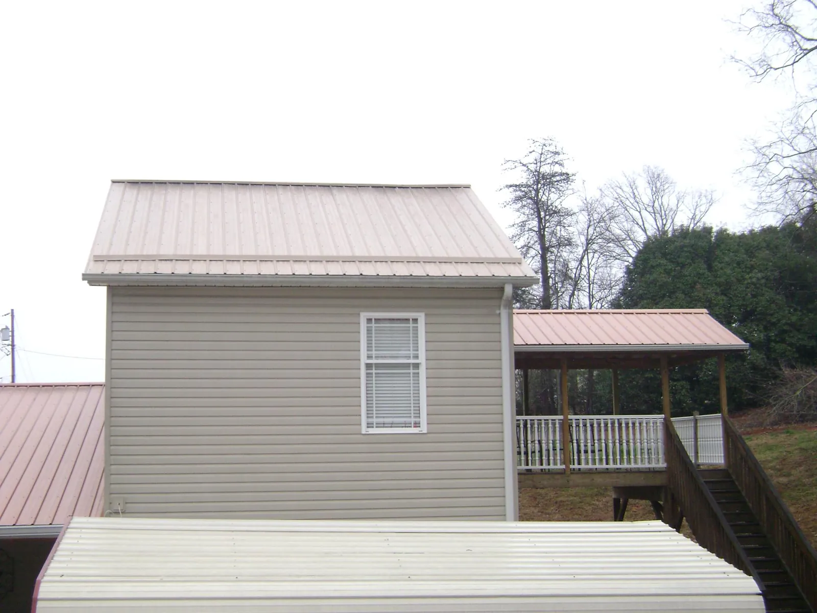 Tan metal roofs on a two story addition and attached porch, from a Roof Replacement job in Coalton