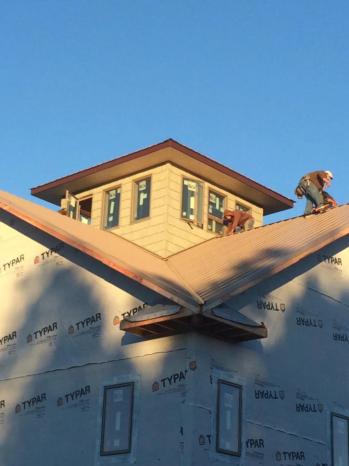 Roofers working around a rooftop cupola on a new metal roof at sunset — Roof Waterproofing in Coalton by Roofing Brothers